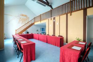 a room with red tables and chairs and a staircase at Comfort Aparthotel Saint-Nazaire Les Portes de l Ocean in Saint-Nazaire