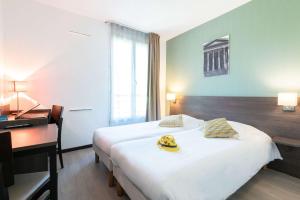 a hotel room with a bed with a desk and bananas on it at Comfort Aparthotel Nimes Centre in Nîmes