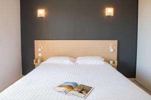 a bedroom with a bed with two books on it at Comfort Aparthotel Frejus La Tour de Mare in Fréjus