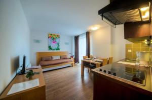 a kitchen and living room with a couch in the background at Comfort Aparthotel Mutzig Portes d'Alsace in Mutzig