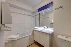 a bathroom with a sink and a tub and a mirror at Comfort Aparthotel Divonne L'Orée du Parc in Divonne-les-Bains +46 photos