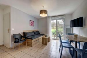 a living room with a couch and a table with chairs at Comfort Aparthotel Divonne L'Orée du Parc in Divonne-les-Bains