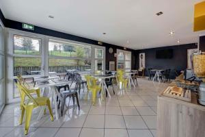a restaurant with yellow chairs and tables and windows at Comfort Aparthotel Divonne L'Orée du Parc in Divonne-les-Bains