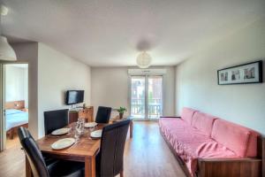 a living room with a pink couch and a table at Comfort Aparthotel Lourdes L'Acacia in Lourdes