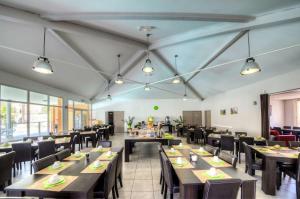 a dining room with tables and chairs and windows at Comfort Aparthotel Lourdes L'Acacia in Lourdes