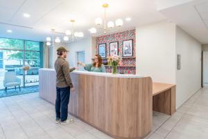 a man standing at a bar in a hospital lobby at Quality Aparthotel Nancy Zenith in Laxou