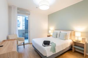 a bedroom with a bed and a chair and a window at Quality Aparthotel Nancy Zenith in Laxou +19 photos