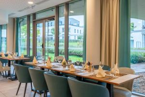a dining room with tables and chairs and windows at Quality Aparthotel Nancy Zenith in Laxou