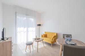 a living room with a yellow couch and a table at Quality Aparthotel Parc Marne la Vallée in Bailly-Romainvilliers