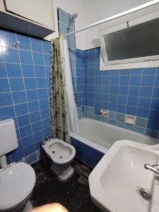 a blue tiled bathroom with a toilet and a sink at Tucumán y Colón in Mar del Plata