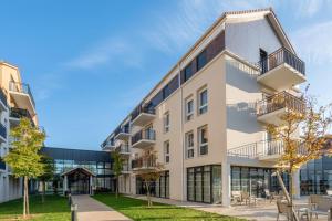 an exterior view of a building with tables and chairs at Quality Aparthotel Moissy-Cramayel in Moissy-Cramayel