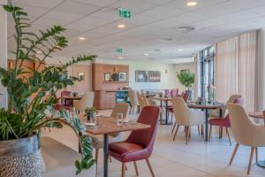a restaurant with tables and chairs and plants at Quality Aparthotel Moissy-Cramayel in Moissy-Cramayel
