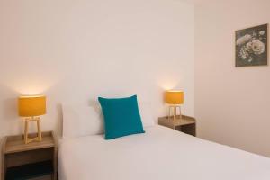 a bedroom with a white bed with two lamps at Quality Aparthotel Orleans Sud Zenith in Olivet