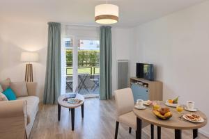 a living room with a couch and a table at Quality Aparthotel Orleans Sud Zenith in Olivet +8 photos