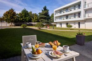 a table with food and drinks on it in front of a building at Quality Aparthotel Orleans Sud Zenith in Olivet