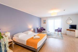 a bedroom with a bed and chairs and a television at Quality Aparthotel Rochefort in Rochefort