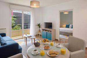a living room with a couch and a table with food on it at Quality Aparthotel Valenciennes in Valenciennes