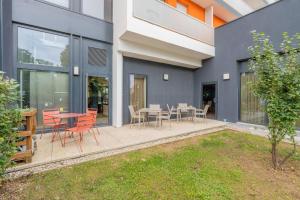 a patio with red chairs and tables on a building at Quality Aparthotel Villefontaine in Villefontaine