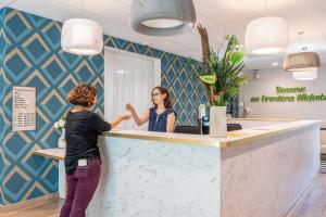 two women standing at a counter in a dental office at Quality Aparthotel Villefontaine in Villefontaine