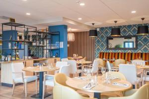 a restaurant with tables and chairs and a bar at Quality Aparthotel Villefontaine in Villefontaine