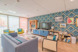 a living room with two couches and a tv at Quality Aparthotel Villefontaine in Villefontaine