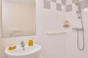 a white bathroom with a sink and a shower at Quality Aparthotel Portes de Rennes in Bruz +13 photos