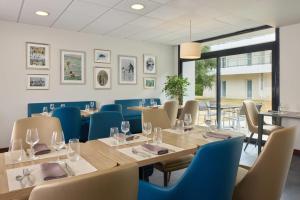 a dining room with a long table and chairs at Quality Aparthotel Portes de Rennes in Bruz