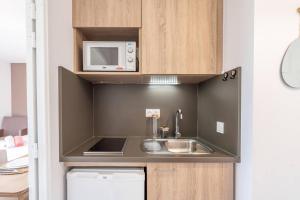 a small kitchen with a sink and a microwave at Quality Aparthotel Lyon L'Isle-d Abeau in LʼIsle-dʼAbeau