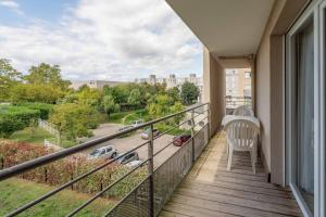 a balcony with a chair and a view of a street at Quality Aparthotel Lyon L'Isle-d Abeau in LʼIsle-dʼAbeau
