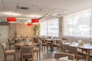 a restaurant with tables and chairs and a large window at Quality Aparthotel Lyon L'Isle-d Abeau in LʼIsle-dʼAbeau