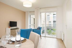 a dining room with a table and blue chairs at Quality Aparthotel Saint-Malo in Saint Malo