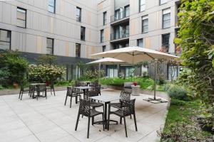 a patio with tables and chairs and an umbrella at Quality Aparthotel Saint-Malo in Saint Malo