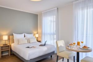 a bedroom with a bed and a table with a laptop at Quality Aparthotel Nancy Centre in Nancy +28 photos