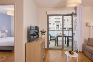 a living room with a bed and a television and a table at Quality Aparthotel Pau Porte Des Pyrénées in Pau
