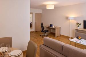 a living room with a couch and a desk at Quality Aparthotel Pau Porte Des Pyrénées in Pau