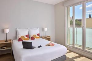 a bedroom with a white bed with a laptop on it at Quality Aparthotel Reims - Saint-Thomas in Reims