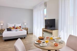 a hotel room with a bed and a table with food at Quality Aparthotel Reims - Saint-Thomas in Reims