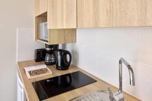 a kitchen counter with a coffee maker and a plate of food at Quality Aparthotel Reims - Saint-Thomas in Reims