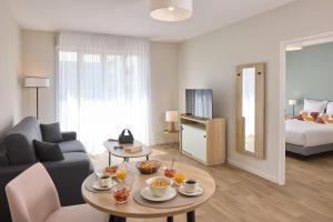a living room with a couch and a table at Quality Aparthotel Reims - Saint-Thomas in Reims +21 photos