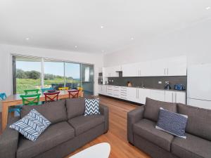 a living room with two couches and a kitchen at 41 Ocean in Anna Bay