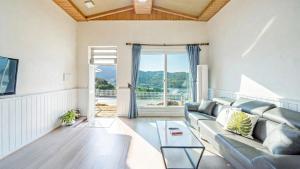 a living room with a couch and a large window at Yeosu Sky Pension in Yeosu