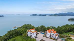 an aerial view of a house on a hill next to a lake at Yeosu Sky Pension in Yeosu