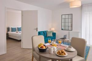 a dining room with a table with a bowl of fruit at Quality Aparthotel Morangis Orly in Morangis +10 photos