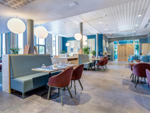 a restaurant with blue walls and tables and chairs at Quality Aparthotel Morangis Orly in Morangis