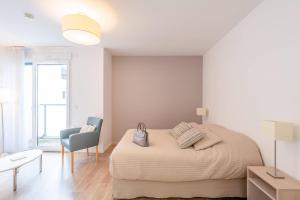 a white bedroom with a bed and a chair at Quality Aparthotel Bourgoin-Jallieu in Bourgoin +11 photos