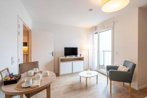 a living room with a table and chairs and a television at Quality Aparthotel Bourgoin-Jallieu in Bourgoin