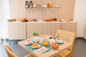 a wooden table with breakfast foods on it at Quality Aparthotel Bourgoin-Jallieu in Bourgoin