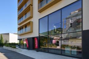 an external view of a building with large glass windows at Quality Aparthotel Voiron in Voiron