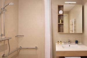 a bathroom with a sink and a shower and a mirror at Quality Aparthotel Voiron in Voiron +16 photos