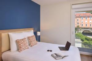 a bedroom with a bed with a laptop and a window at Quality Aparthotel Voiron in Voiron
